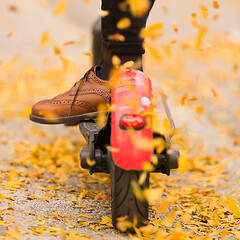 Image showing Detail of fashinable hipster girl riding electric scooter in park at fall