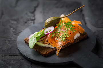Image showing Salmon open sandwich on Pumpernickel bread with vegetables, herbs and soft cheese