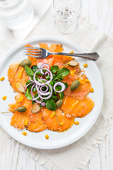 Image showing Salmon carpaccio and arugula salad with onions and capers