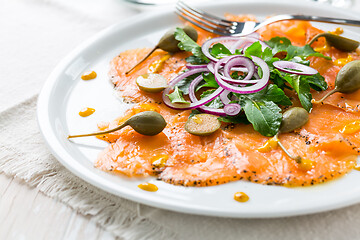 Image showing Salmon carpaccio and arugula salad with onions and capers