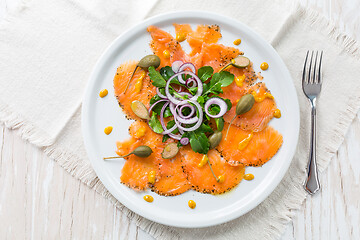 Image showing Salmon carpaccio and arugula salad with onions and capers