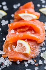 Image showing Smoked salmon with lemon and sea salt on black background