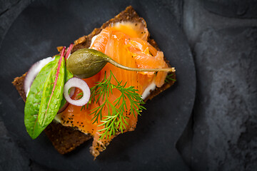 Image showing Salmon open sandwich on Pumpernickel bread with vegetables, herbs and soft cheese