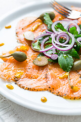 Image showing Salmon carpaccio and arugula salad with onions and capers