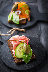 Image showing Variation of healthy open sandwiches on Pumpernickel bread with vegetables, salmon, ham, herbs and soft cheese