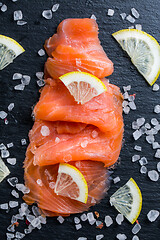 Image showing Smoked salmon with lemon and sea salt on black background