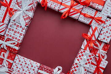 Image showing Arranged Gifts boxes wrapped in colorful festive paper with on burgund background