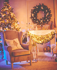 Image showing Christmas interior concept. With fireplace, armchair, pine tree, wrapped gifts, lights