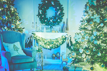 Image showing Christmas interior concept. With fireplace, armchair, pine tree, wrapped gifts, lights