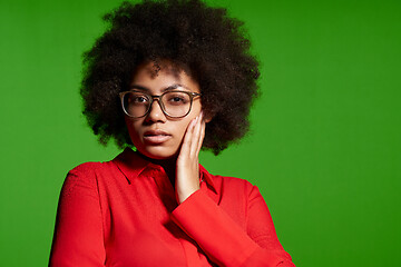 Image showing Thinking young African-American girl in glasses and red shirt looking at camera