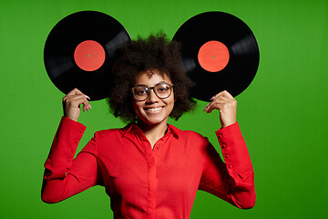 Image showing Funny African-American girl in red shirt holding vinyl disc as ears