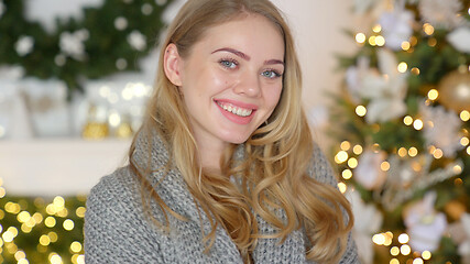 Image showing Fashionable smiling woman wearing knitwear cozy sweater in front of christmas tree