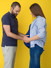Image showing pregnant couple  isolated over yellow background