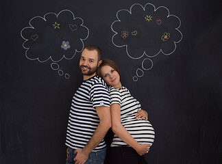 Image showing pregnant couple posing against black chalk drawing board