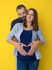 Image showing pregnant couple  isolated over yellow background