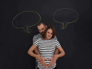 Image showing pregnant couple posing against black chalk drawing board