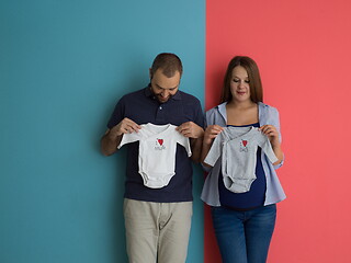 Image showing young couple holding baby bodysuits