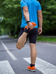 Image showing male runner warming up and stretching before morning training