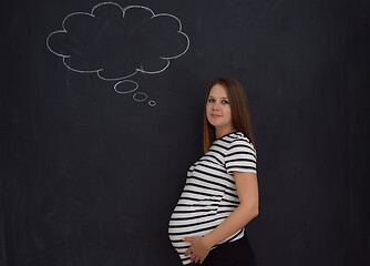 Image showing pregnant woman thinking in front of black chalkboard