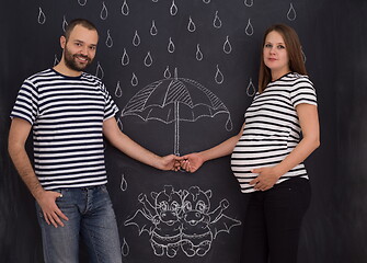 Image showing pregnant couple drawing their imaginations on chalk board