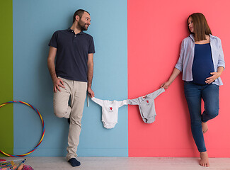 Image showing young couple holding baby bodysuits