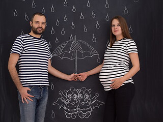 Image showing pregnant couple drawing their imaginations on chalk board