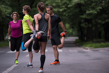 Image showing runners team warming up and stretching before morning training