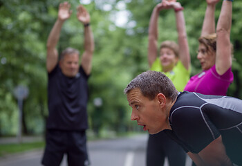 Image showing runners team warming up and stretching before morning training