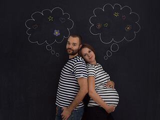 Image showing pregnant couple posing against black chalk drawing board