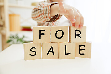 Image showing Wooden cubes with words sale in hands of happy smiling little boy at home