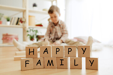 Image showing Wooden cubes with words HAPPY FAMILY in hands of little boy