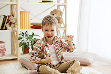 Image showing Little child sitting on the floor. Pretty boy palying with wooden cubes at home