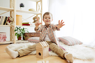 Image showing Little child sitting on the floor. Pretty boy palying with wooden cubes at home