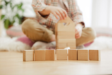 Image showing Little child sitting on the floor. Pretty boy palying with wooden cubes at home