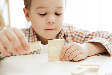 Image showing Little child sitting on the floor. Pretty boy palying with wooden cubes at home