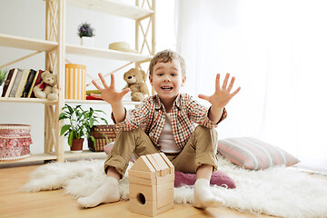 Image showing Little child sitting on the floor. Pretty boy palying with wooden cubes at home