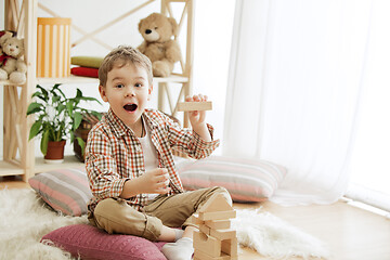 Image showing Little child sitting on the floor. Pretty boy palying with wooden cubes at home