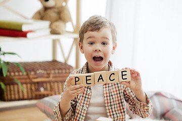 Image showing Wooden cubes with word PEACE in hands of little boy