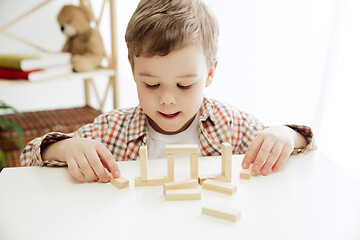 Image showing Little child sitting on the floor. Pretty boy palying with wooden cubes at home