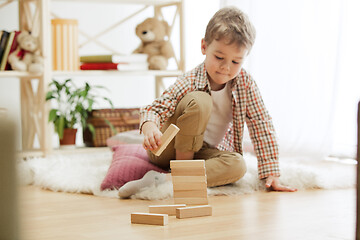 Image showing Little child sitting on the floor. Pretty boy palying with wooden cubes at home