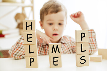 Image showing Wooden cubes with words HELP ME PLS in hands of little boy