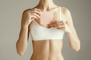 Image showing Young adult woman holding empty paper card for sign or symbol.