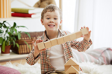 Image showing Little child sitting on the floor. Pretty boy palying with wooden cubes at home