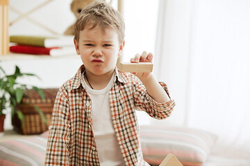 Image showing Little child sitting on the floor. Pretty boy palying with wooden cubes at home