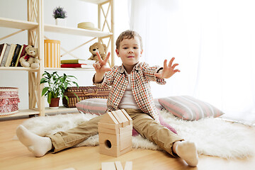 Image showing Little child sitting on the floor. Pretty boy palying with wooden cubes at home