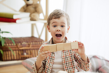 Image showing Little child sitting on the floor. Pretty boy palying with wooden cubes at home