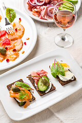 Image showing Variation of healthy open sandwiches on Pumpernickel bread with vegetables, salmon, Prosciutto and appetizers