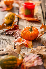 Image showing Pumpkins with candles and autumn leaves on wooden background