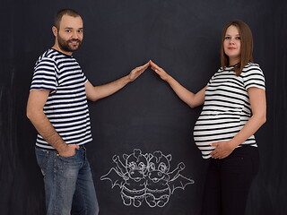 Image showing pregnant couple drawing their imaginations on chalk board