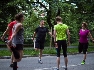 Image showing runners team warming up and stretching before morning training